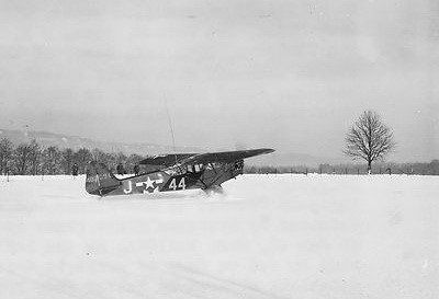 « Aérodrome de La Platte » : Derrière le Piper Cub des soldats américains. En arrière-plan, les tilleuls de la route du Tonnelet et la colline de Balmoral. L’appareil a le nez tourné vers Nivezé.