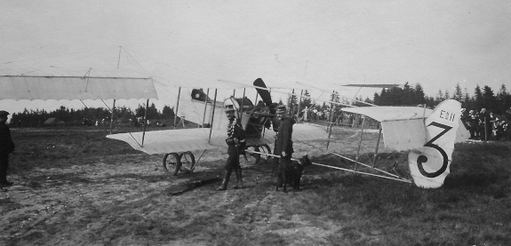 Aérodrome de Bellefagne situé sur la fagne de Malchamps. Grande Quinzaine de l’Aviation du 20 septembre au 5 octobre 1909. Devant l’avion, à droite avec son chien, le garde-champêtre nivezétois.