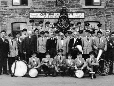 6 août 1961 : 50e anniversaire du « Réveil Sartois ».
La fanfare et les autorités communales sartoises posent devant le deuxième local de la fanfare, situé Place du Marché et dénommé « Café Sente »
Aujourd’hui, cet établissement a été transformé en appartements, il se situe à côté de l’épicerie de « Jenny »
