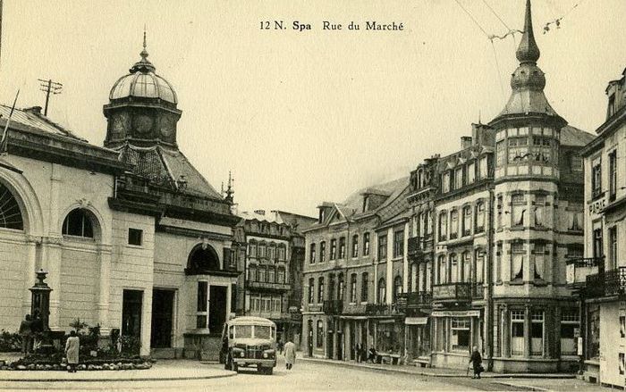 1950 : Rue du Marché. La galerie-promenoir couverte et la demi-rotonde du Pouhon ont été démontées en 1948 pour permettre l’installation de la fontaine en pierre. De nos jours, cette fontaine se trouve au pied du funiculaire suite à la restauration du Pouhon en 2013 et à la remise en place d’une nouvelle galerie-promenoir couverte.